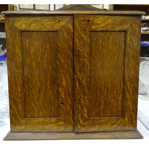 118 - An oak smoker's cabinet fitted with a pair of doors opening to reveal two drawers and a revolving pi... 