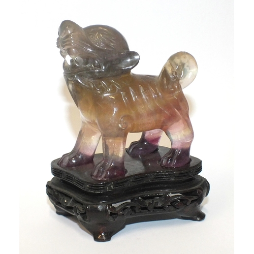 214 - A Chinese hardstone carving of a standing kylin, on a carved wood base, 10cm.