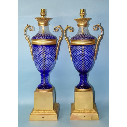 231 - A pair of contemporary gilt-metal-mounted blue overlay glass table lamps of two-handled urn shape, o... 