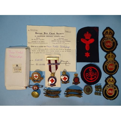 800 - A British Red Cross Society three years service medallion and various metal and cloth badges for VAD... 