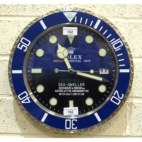 162 - A Rolex-style dealers circular battery-operated wall clock with blue rim, 34cm diameter.... 