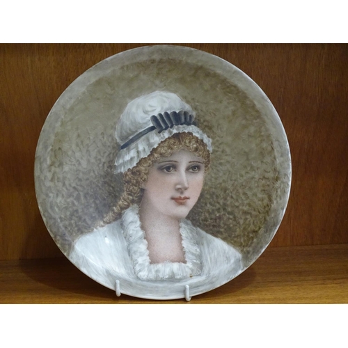 124 - A pair of Derby ceramic plates, each painted with a portrait of a young woman wearing a mob cap, 23.... 