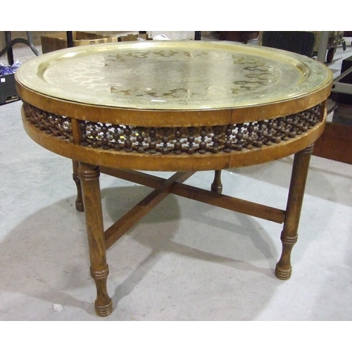 108 - A large brass Benares circular tray, 70cm diameter, set in a low wood table with pierced frieze, on ... 