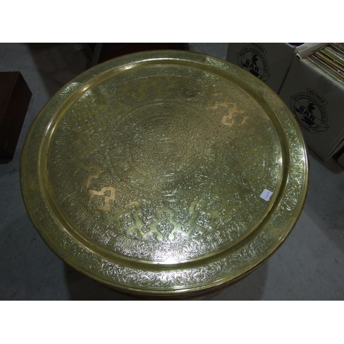 108 - A large brass Benares circular tray, 70cm diameter, set in a low wood table with pierced frieze, on ... 