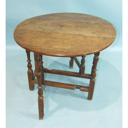 29 - An antique oak drop-leaf low table on turned gate leg, 89cm long, 83cm wide, (split to top, old repa... 
