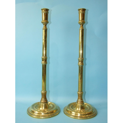 72 - A pair of brass 19th century tall candle holders on turned circular bases, 43cm high and three other... 