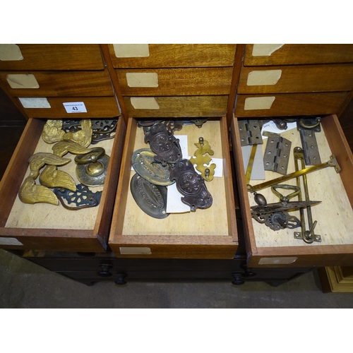 43 - A wooden nest of eighteen drawers containing various brass and metal door furniture and fittings, 59... 