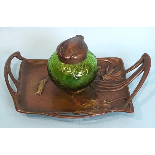 154 - An early-20th century German copper inkwell in the Art Nouveau style, with floral detail and green g... 