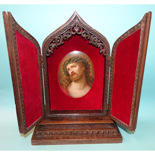 168 - A well-carved oak icon holder in the form of a Gothic arch, the two hinged doors revealing a painted... 