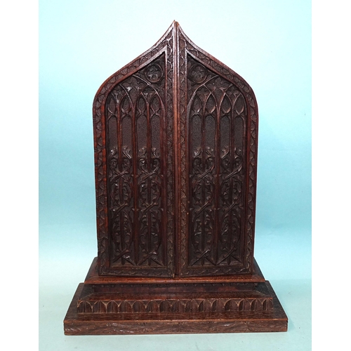 168 - A well-carved oak icon holder in the form of a Gothic arch, the two hinged doors revealing a painted... 