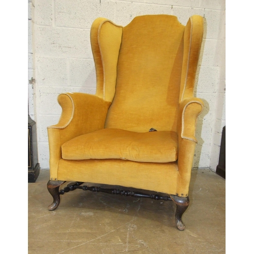 89 - A large generous-seated wing armchair on short cabriole legs joined by stretchers and an upholstered... 