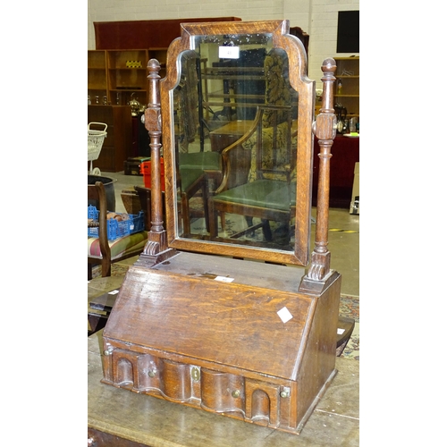 90 - An oak dressing table mirror in the form of a fall-front bureau, with fitted interior and shaped bev... 