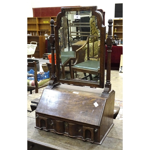 90 - An oak dressing table mirror in the form of a fall-front bureau, with fitted interior and shaped bev... 