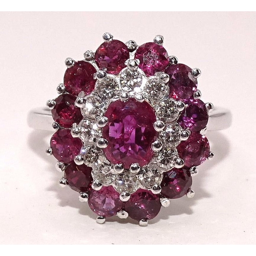 432 - A ruby and diamond cluster ring claw-set an oval ruby within concentric borders of twelve each brill... 