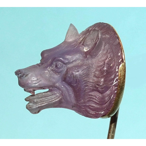 596 - A Queen Victoria interest gold stick pin surmounted by a carved amethyst wolf's head, the mount engr... 