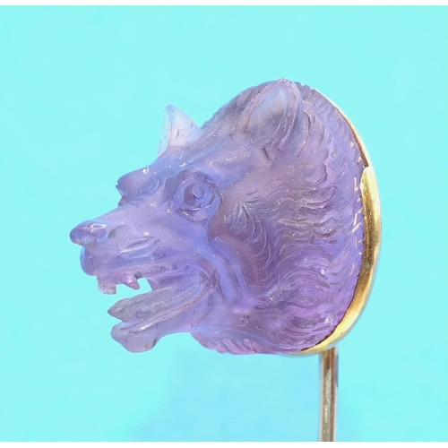 596 - A Queen Victoria interest gold stick pin surmounted by a carved amethyst wolf's head, the mount engr... 