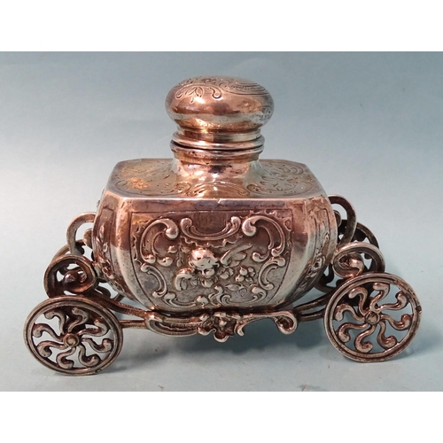 759 - A silver inkwell of Baroque form, raised on ornate carriage with four wheels, 9cm high, 12.5cm long,... 