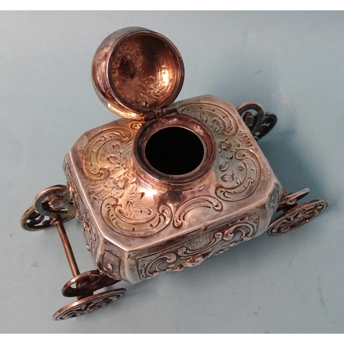 759 - A silver inkwell of Baroque form, raised on ornate carriage with four wheels, 9cm high, 12.5cm long,... 