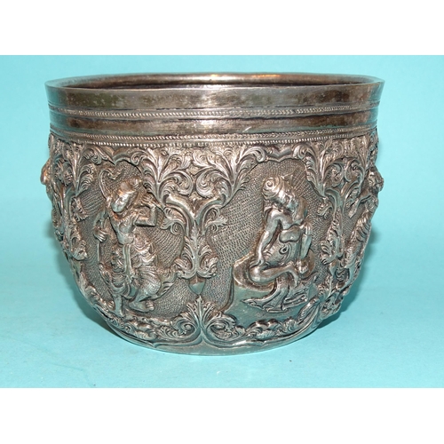 767 - A Burmese silver bowl deeply embossed with deities within scrolling arches, 12.5cm diameter, 9.5cm d... 