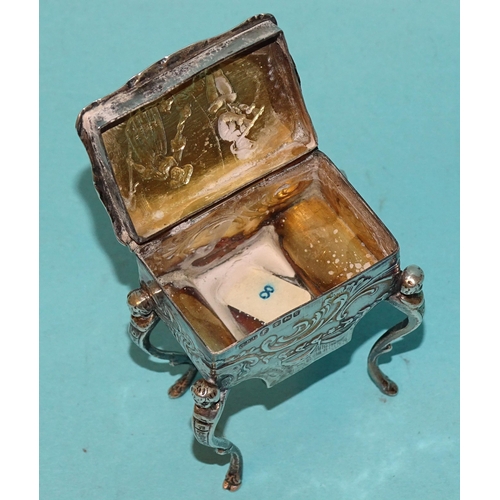 917 - A Continental silver pill box in the form of a worktable, on cabriole legs, with embossed decoration... 