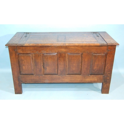 100 - An antique oak panelled coffer, the lift lid above plain fielded panels and stiles extended to form ... 