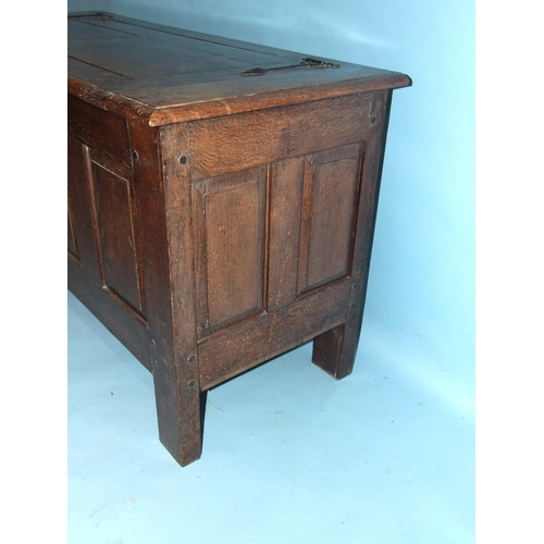 100 - An antique oak panelled coffer, the lift lid above plain fielded panels and stiles extended to form ... 