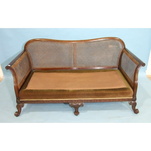 104 - A 20th century mahogany Bergère caned settee with outswept arms, on blind-fret frame and carv... 