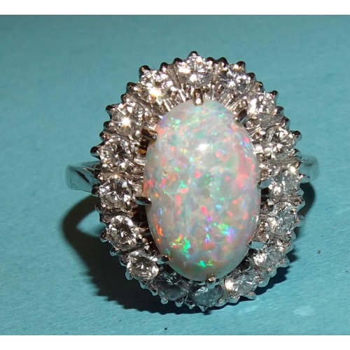 296 - An opal and diamond cluster ring claw-set an oval opal, 12.5 x 8mm, within a surround of sixteen bri... 