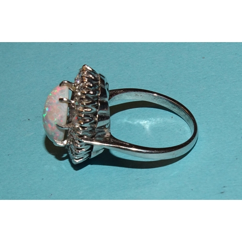 296 - An opal and diamond cluster ring claw-set an oval opal, 12.5 x 8mm, within a surround of sixteen bri... 