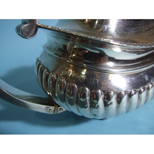 566 - A George III silver teapot of oval boat shape, with half-reeded decoration and leaf-capped C-scroll ... 