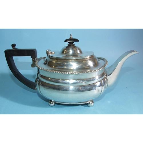 567 - A 20th century plain teapot with gadrooned border, on ball feet, with black handle and finial, Londo... 