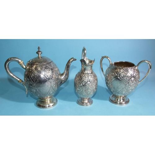 586 - A Victorian silver teapot of ovoid form with all-over decoration of flowers and scrolls, on circular... 