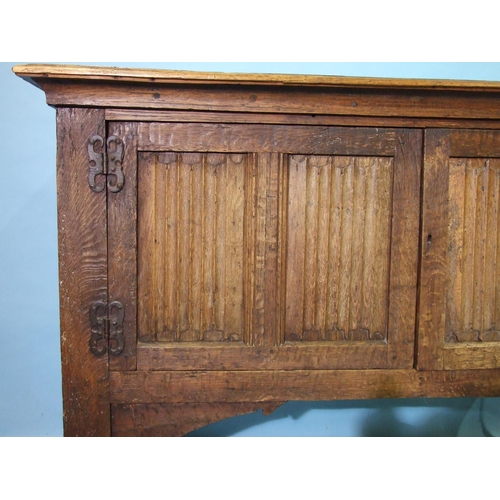 99 - An antique oak side cupboard, having a pair of linen-fold doors, on extended stile supports, 150cm w... 