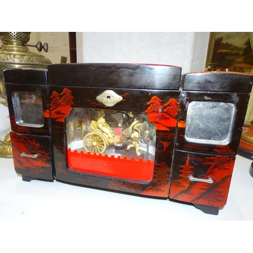 121 - A lacquered musical jewellery box with figural scene and three small mirrored display stands, (one l... 