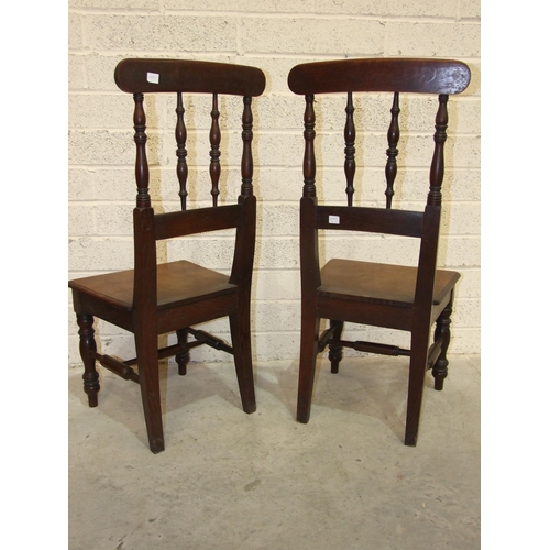 64 - A pair of 19th century oak hall chairs, each with turned spindle back and solid seat, on tapered fro... 