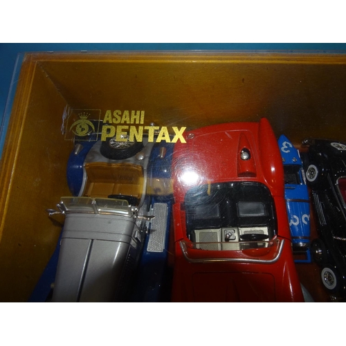 125 - A collection of 32 diecast and plastic cars in an Asahi Pentax plywood and Perspex display case.... 