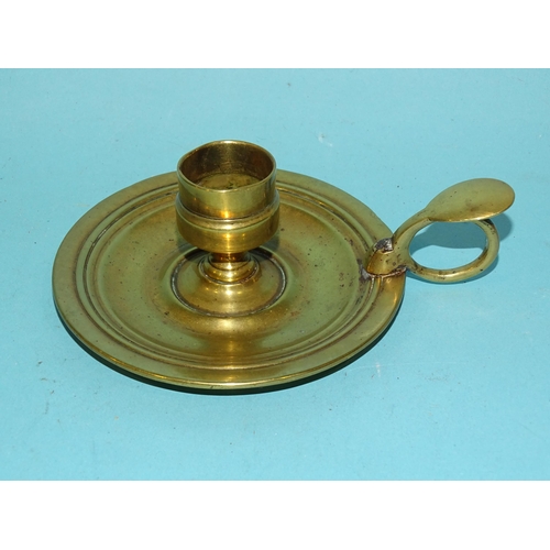 115 - An 18th century brass chamberstick, the circular base with early screw-mounted sconce and finger loo... 