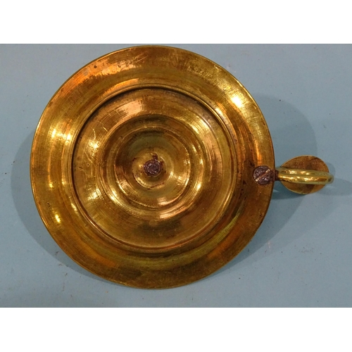 115 - An 18th century brass chamberstick, the circular base with early screw-mounted sconce and finger loo... 