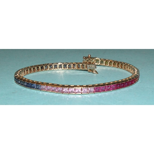 232 - A rainbow sapphire tennis bracelet set a total of sixty-five scissor-cut fancy colour sapphires in g... 