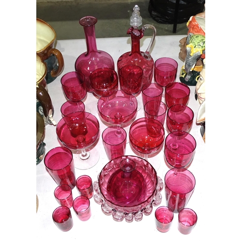 49 - A cranberry glass decanter, 27cm high, a circular frilled bowl and a collection of cranberry glasses... 