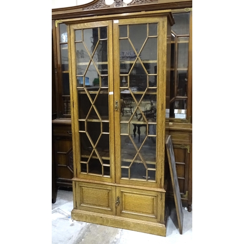 5 - A 20th century oak two-door bookcase having a pair of astragal-glazed doors above two small panelled... 