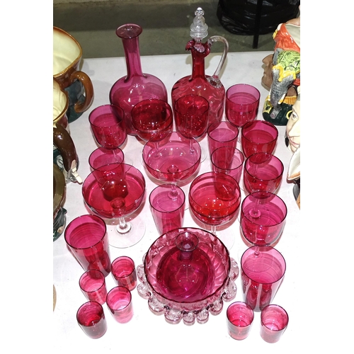 131 - A cranberry glass decanter, 27cm high, a circular frilled bowl and a collection of cranberry glasses... 