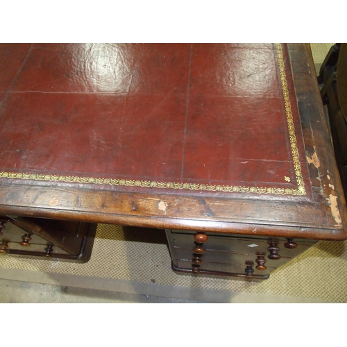 19 - A stained pine kneehole desk, the leather-inset top above a central drawer, eight pedestal drawers a... 