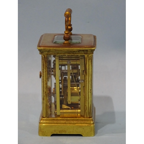 126 - A late-19th/early-20th century brass miniature carriage alarm clock, the white enamel face with dial... 