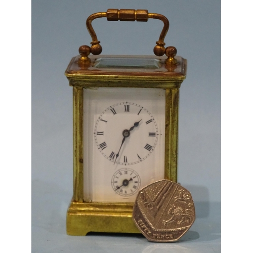 126 - A late-19th/early-20th century brass miniature carriage alarm clock, the white enamel face with dial... 