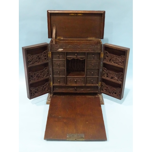 153 - A Continental carved stained wood collector's chest, with fall-front enclosing an interior fitted wi... 