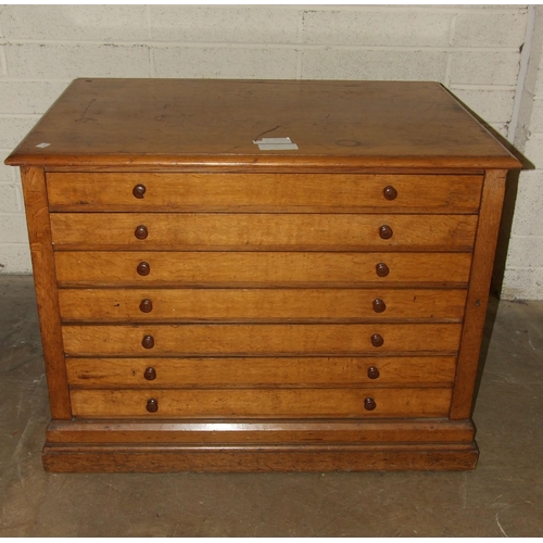 67 - An Edwardian oak plan chest of seven drop-down-fronted drawers, on plinth base and panelled back, wi... 