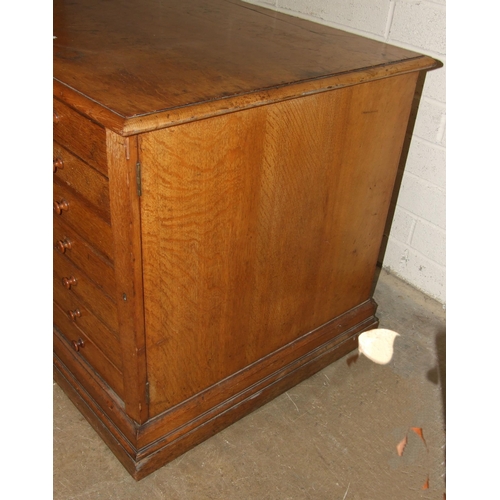 67 - An Edwardian oak plan chest of seven drop-down-fronted drawers, on plinth base and panelled back, wi... 