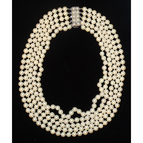 26 - A late-20th century necklace of five strands of uniform cultured pearls, with white gold pearl-set c... 