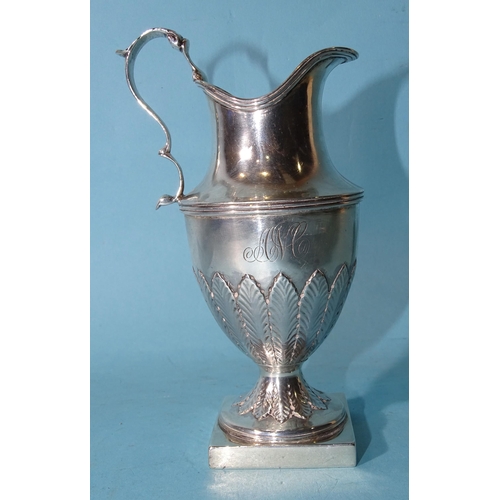 478 - A George III silver urn shape pedestal cream jug on square base with scrolling handle and leaf decor... 